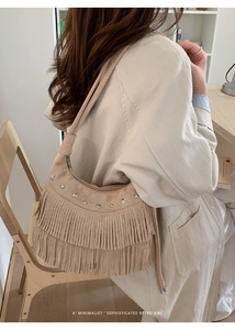 Detail of beige suede shoulder bag with long fringes and silver star metal rivets