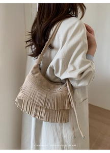 Detail of beige suede fringe bag with star-shaped metal studs and retro tassels