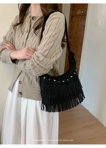 Detail of black suede shoulder bag featuring silver star studs and long vintage tassels