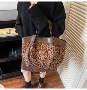 Detail of leopard print canvas tote bag with brown leather handles and silver studs