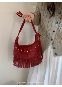 Detail of red suede tassel bag with silver star studs and bohemian fringe details