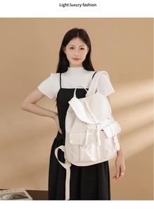 Dettaglio di uno zaino bianco in pelle martellata con chiusure a fibbia vintage