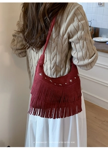 Detailed close-up of dark red suede fringe bag with silver star studs and retro bohemian style
