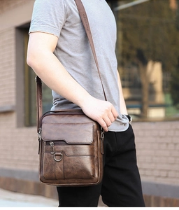 Close-up of vintage brown PU leather texture and durable strap on men's messenger bag