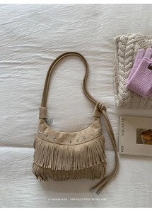 Detail of khaki suede crescent bag featuring star studs and long vintage fringe accents