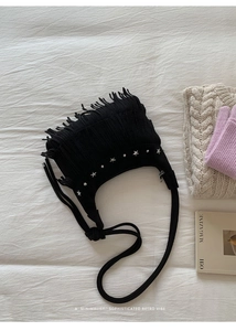 Close-up of black suede fringe bag with silver star rivets and tassel details