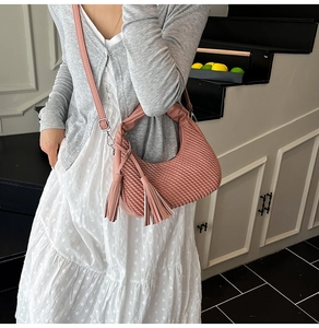 Dettaglio della texture in pelle intrecciata rosa e eleganti nappe doppie sulla borsa