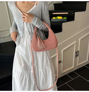 Dettaglio della borsa hobo rosa con trama trapuntata a onde e nappina decorativa in pelle