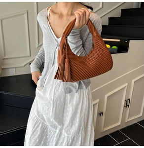 Dettaglio della borsa in pelle intrecciata marrone caramello con lunghe nappe a frange