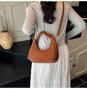 Borsa hobo marrone intrecciata con tracolla regolabile, vista laterale sul modello