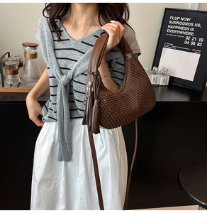 Dettaglio borsa hobo intrecciata marrone scuro con nappa e tracolla sottile elegante