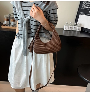 Dettaglio della borsa a mezzaluna marrone intrecciata con elegante nappa laterale
