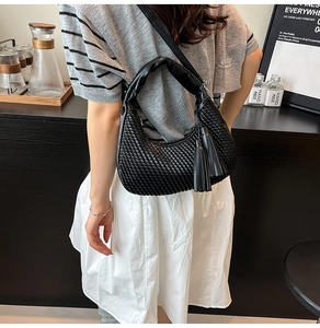 Dettaglio della borsa a tracolla intrecciata nera con lunghe nappe in uno stile casual