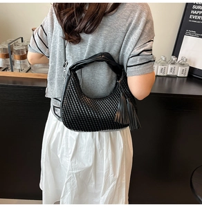 Dettaglio della borsa hobo intrecciata nera con manici lisci e grandi decorazioni con nappe