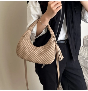 Dettaglio della borsa hobo beige con trama intrecciata e nappa decorativa su modella