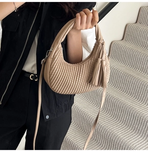 Dettaglio della borsa a mano beige a pieghe con nappina e fibbia in metallo argento