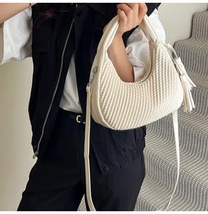 Borsa hobo intrecciata color crema con nappe in pelle indossata da una modella per look