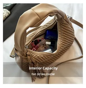 Dettaglio della capacità interna della borsa a tracolla intrecciata kaki con oggetti quotidiani