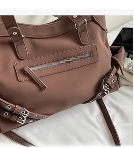 Detail of dark brown vintage motorcycle bag with silver eyelets and matte leather texture