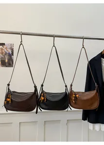 Detail view of crescent crossbody bags in brown, black, and tan with beaded tassels