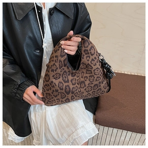 Detail of hobo handbag featuring leopard print pattern and black knot tie on suede fabric