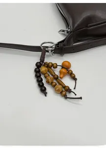 Detail of beaded wood charm and orange gourd pendant on a dark brown leather bag