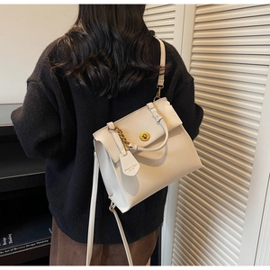 Détail du sac à main en cuir crème avec anse en chaîne dorée et fermoir pivotant