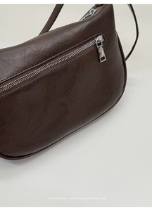 Detail shot of the back zipper pocket on a dark brown leather crossbody dumpling bag