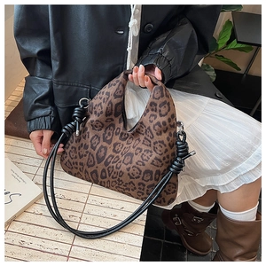 Detail of leopard print handbag with unique black knotted strap and curved silhouette