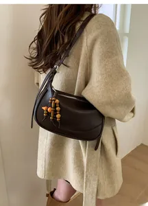 Detail of dark brown crescent bag with unique wooden bead tassel worn on shoulder