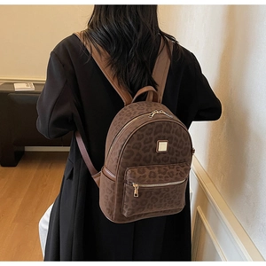 Close-up of leopard print backpack with brown leather straps and gold zippers