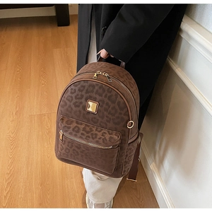Detailed close-up of leopard print backpack with gold zipper and metal logo plaque