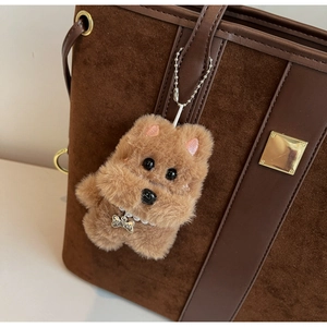 Close-up of brown plush dog charm with pearl collar and Top Dog tag on a leather bag