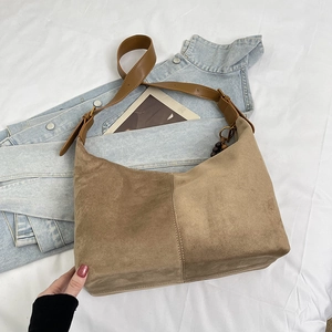 Detail of khaki brown suede hobo bag with wide leather strap and vintage bead pendant