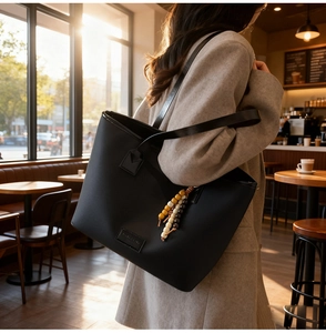 Detail of black pebbled leather tote bag with colorful beads and long shoulder strap