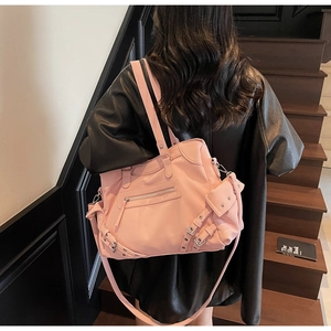 Detail of pink motorcycle handbag featuring rivet studs and leather tassel accents