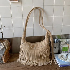 Khaki suede hobo bag with bohemian fringe and star studs on a wooden table