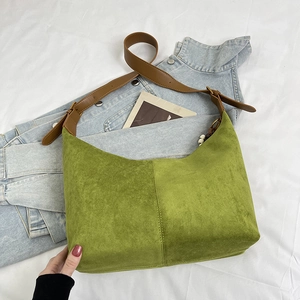 Detail view of large green suede tote bag with brown adjustable strap and contrast stitching