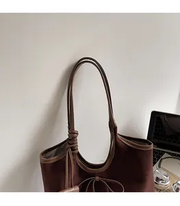 Close-up of the comfortable leather shoulder strap on a brown suede tote bag