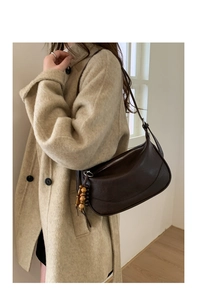 Detail of dark brown leather crescent bag with retro wooden bead charm and metal zipper