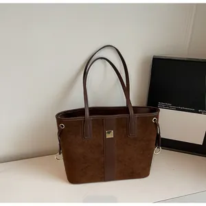Detail view of dark brown suede tote bag with smooth leather straps and metal buckle