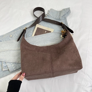 Detail of suede hobo bag with adjustable strap and vintage beaded tassel ornament