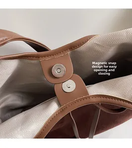 Detail of the dual magnetic closure and herringbone fabric lining on a brown tote bag
