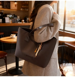 Detail of dark brown leather tote bag with colorful bead tassel hanging on the side