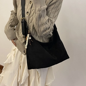 Detail view of black suede crescent tote with wooden beads and leather strap