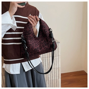 Close-up of a burgundy leopard print knit shoulder bag with black braided rope handles