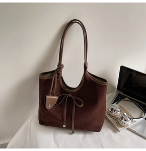 Detail of dark brown faux suede tote bag with bow decoration and silver metal beads
