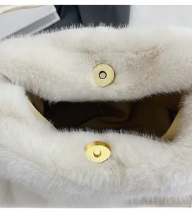 Detailed close-up of a white faux fur shoulder bag featuring a gold magnetic metal clasp