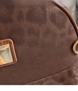 Close-up of brown suede fabric texture with gold metal square buckle and leather trim