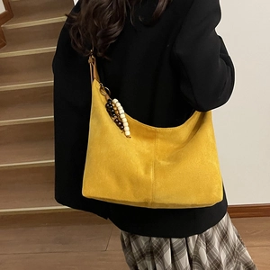 Close-up of mustard yellow suede hobo bag featuring decorative wooden bead charms